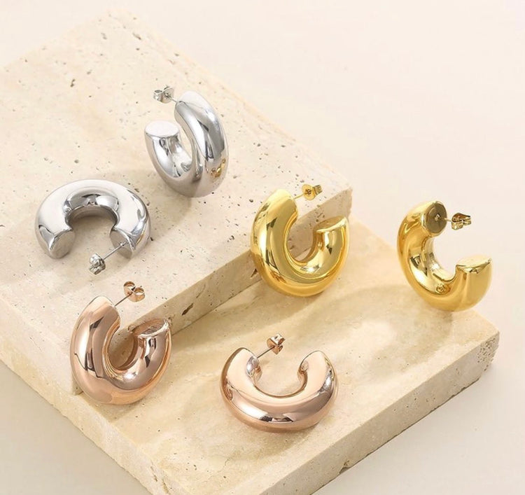 chunky hoop earrings in gold, silver and rose gold on top of a stone 