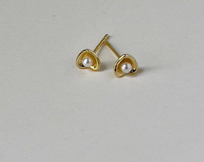 close up of heart shaped earrings in gold with faux pearl detail