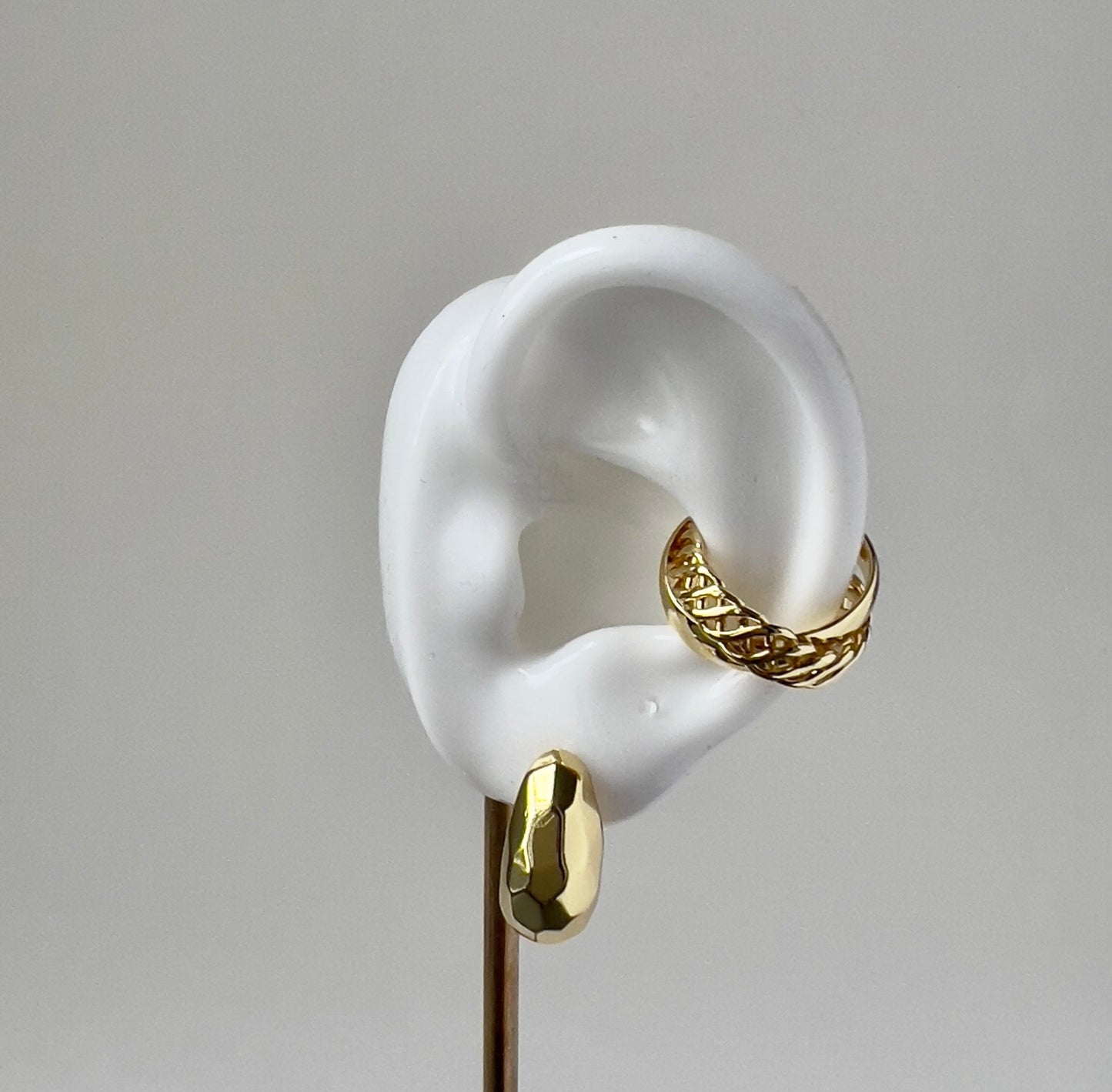 geometrical gold huggie earring on a white ear