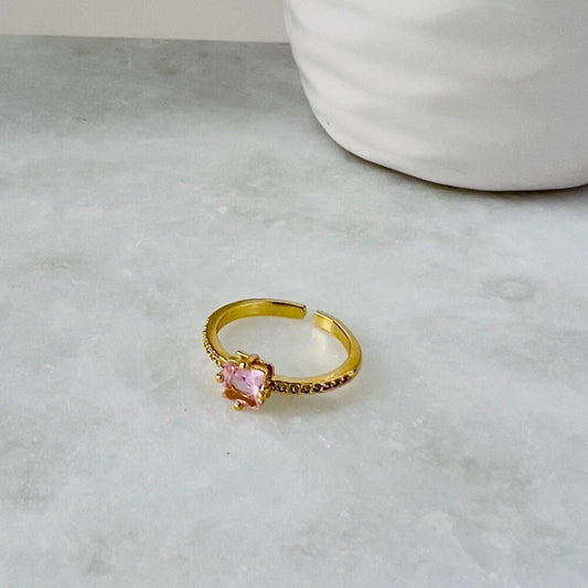 pink ring with squared rose pink crystal laying on a marble surface perfect to give away to a friend or as the perfect gift for an undergraduate