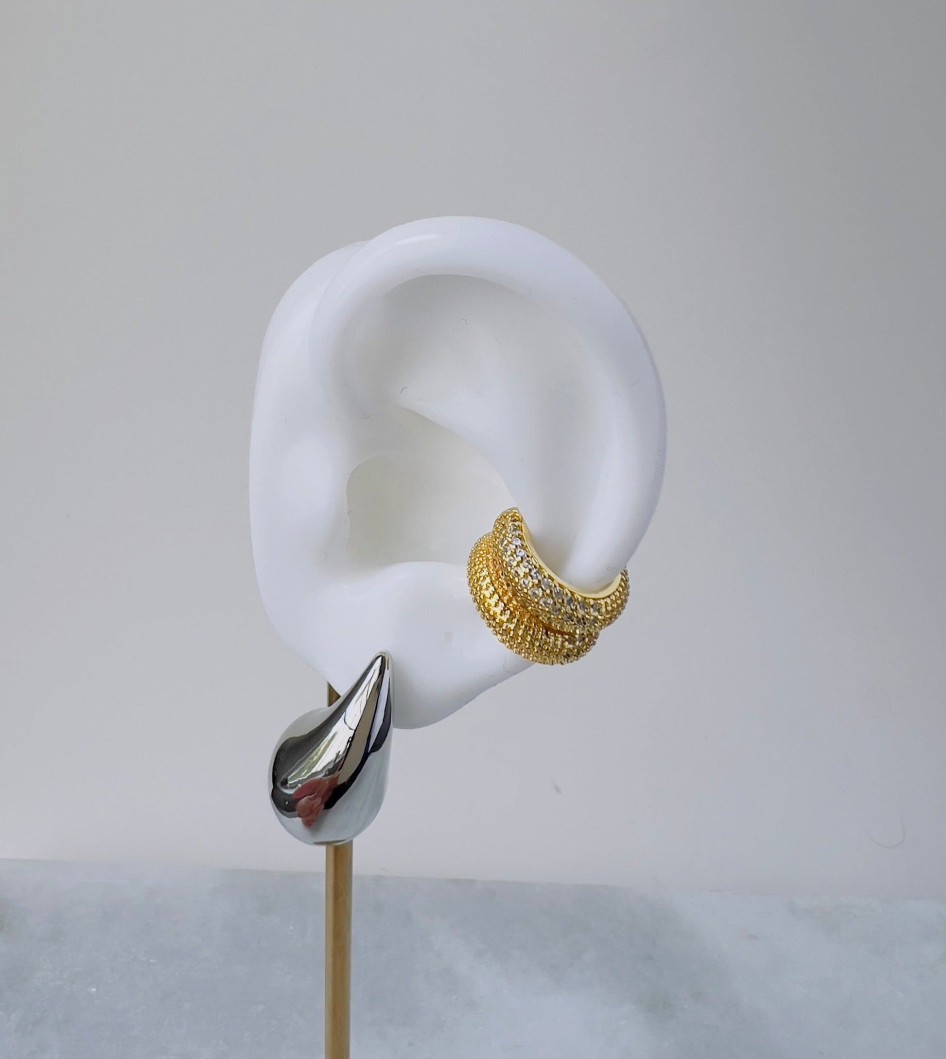 small ear cuff in gold and cubic zirconia details displayed in a mock up ear