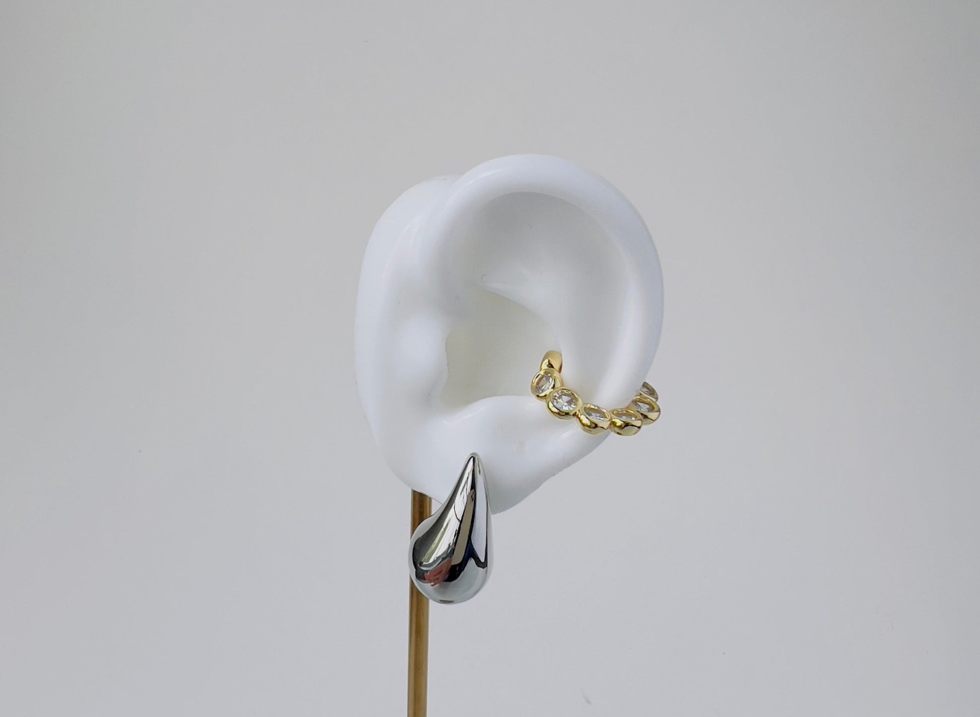 bead style ear cuff with cubic zirconia displayed on silicon ear with silver drop earring