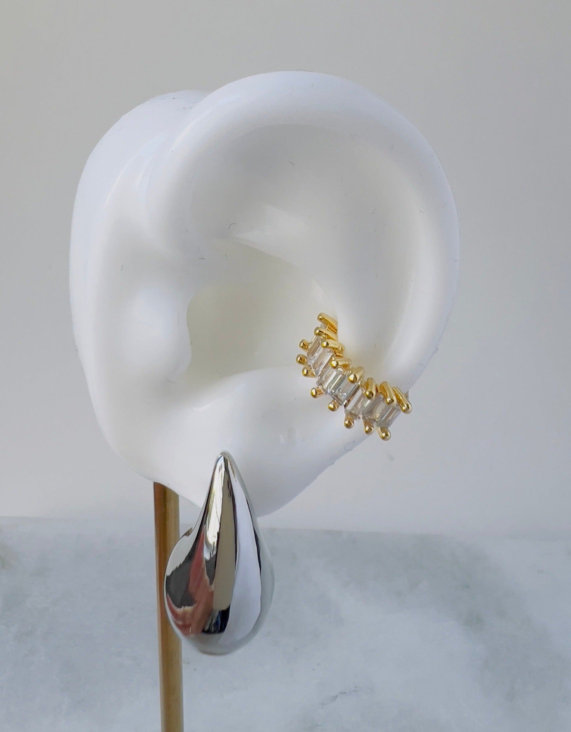 Zirconia ear cuff with gold plated frame in a white ear with a long silver drop earring
