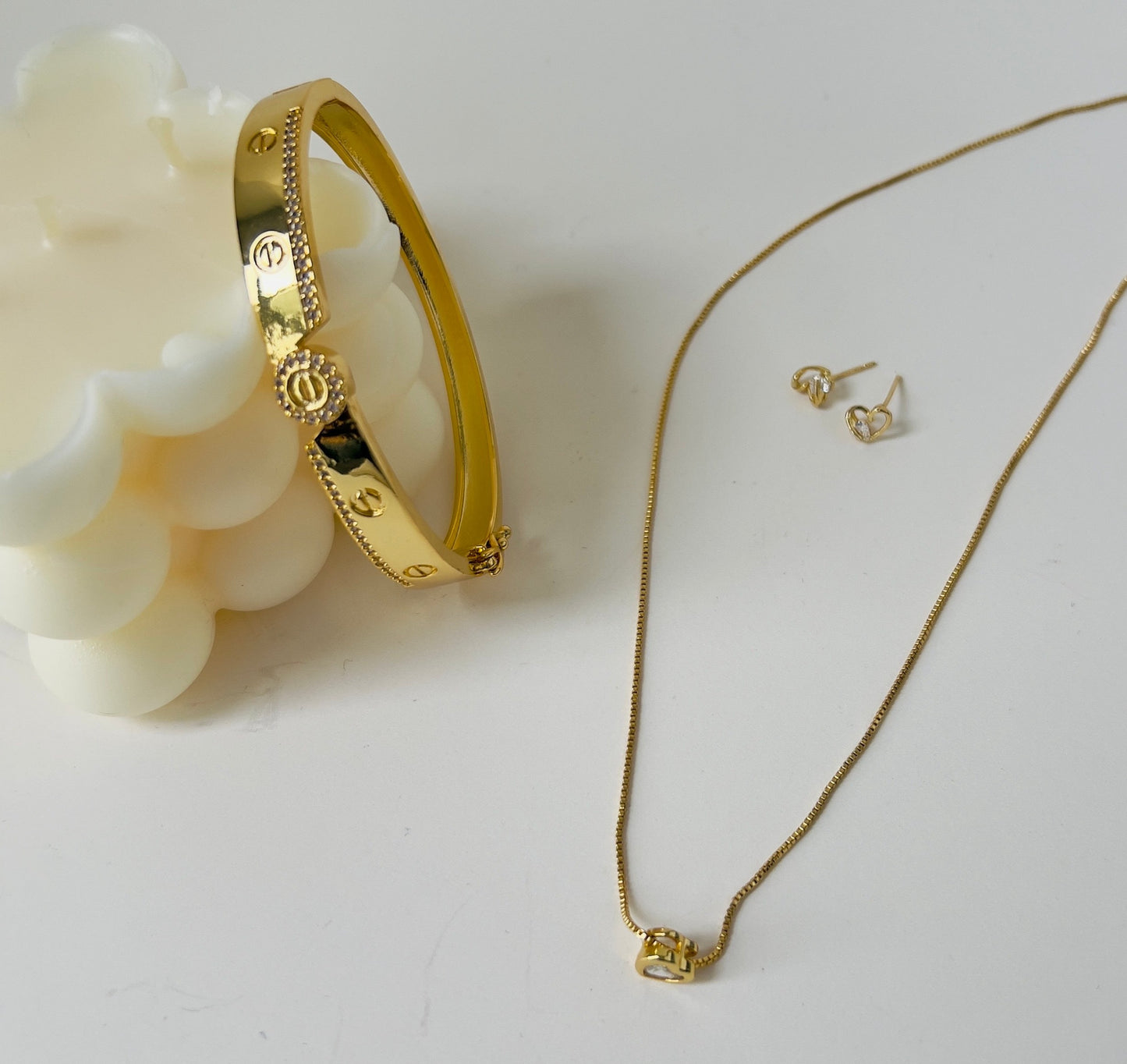 trendy gold bracelet staged with earrings in heart shape