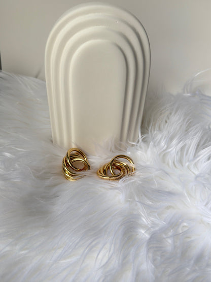 picture of intertwined earrings in gold plated in a bed of feathers