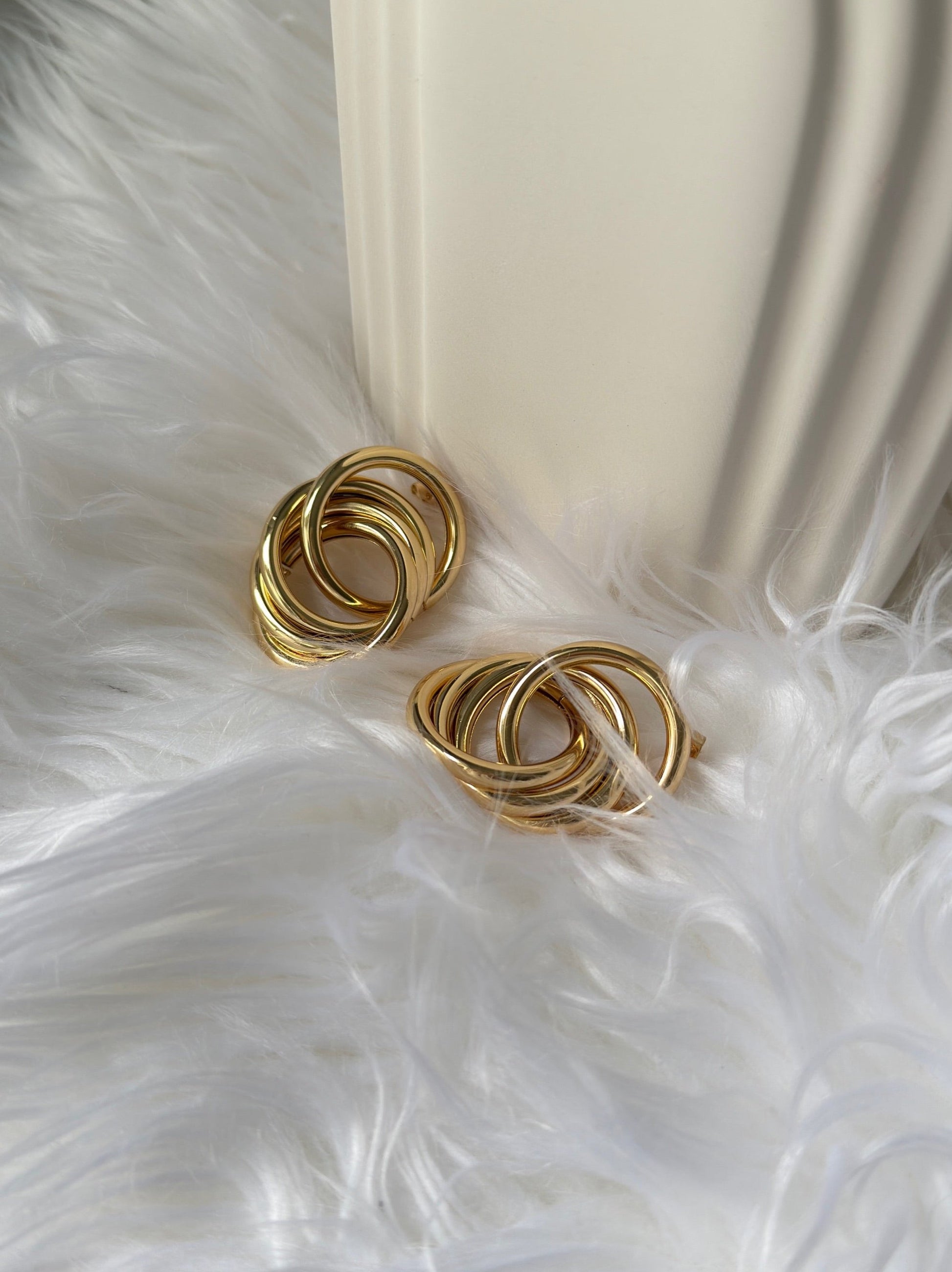 picture of intertwined earrings in gold plated in a bed of feathers