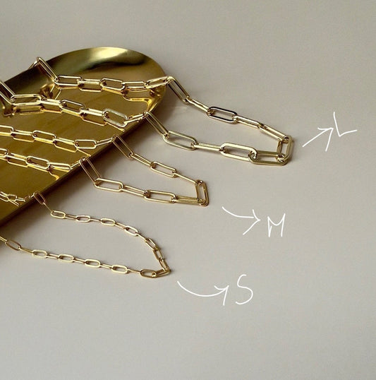 "Flat lay of a gold paperclip necklace placed on a marble surface, showcasing its trendy link design.