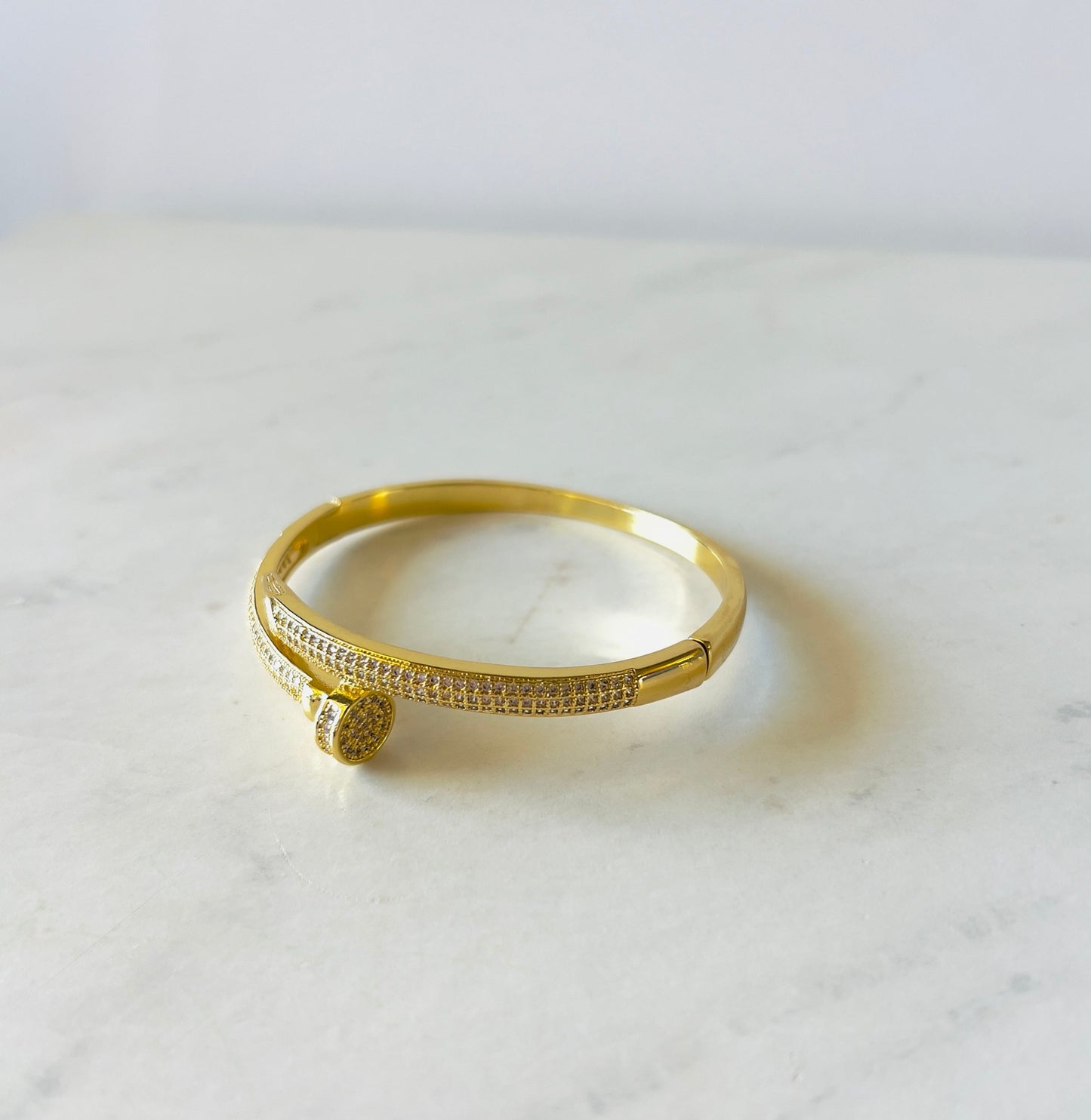 trendy nail shape bangle in gold on white surface