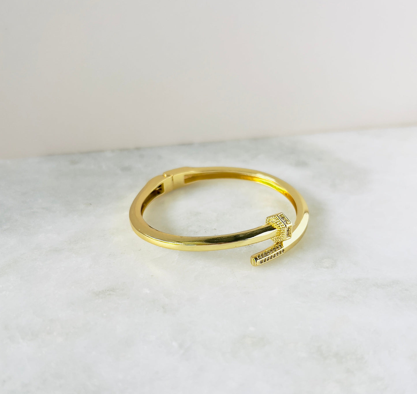 Modern nail-shaped bangle with dazzling zirconia accents, ideal for fashion-forward individuals. This zirconia bangle combines innovative design with sparkling elegance for a standout piece